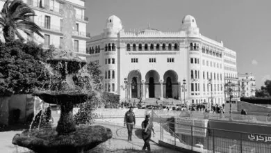 مبنى البريد المركزي في الجزائر العاصمة مع نافورة ماء وأشخاص يمشون في ساحة البريد المركزي
